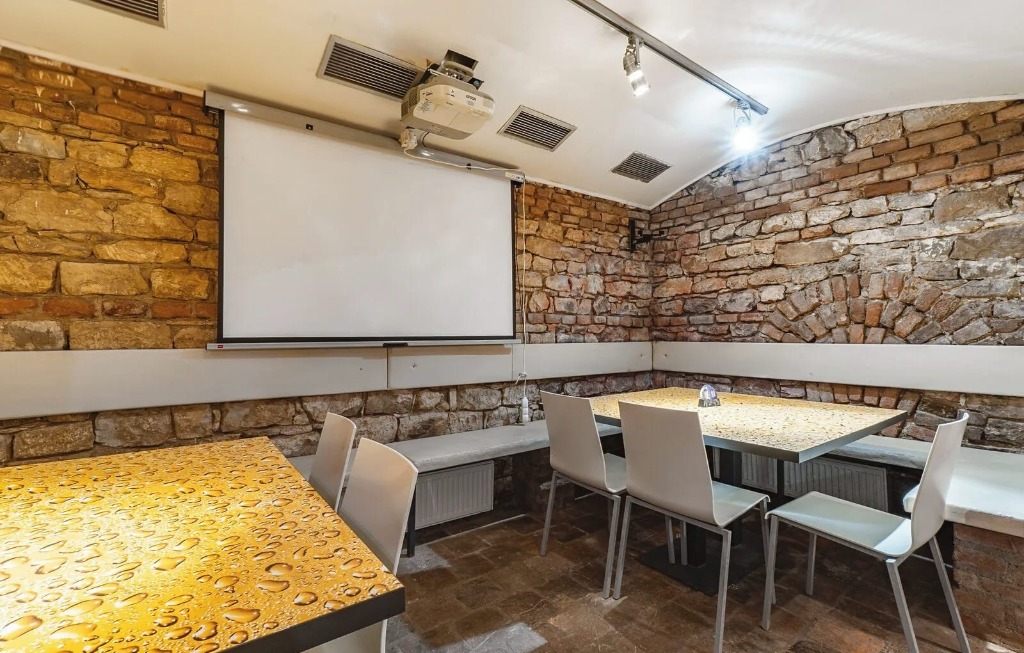 Spodní salonek restaurace U Folimanky s projekčním plátnem a cihlovými zdmi